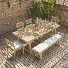 a wooden table with two benches and a potted plant on it in the back yard