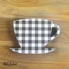 a black and white checkered coffee cup on a wooden table with the lid down