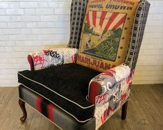 an upholstered chair with graffiti on the back and arms, in front of a brick wall