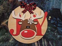 a wooden ornament with a reindeer's head and red bow on it