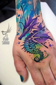 a man's hand with a dragon tattoo on it and watercolor splatters