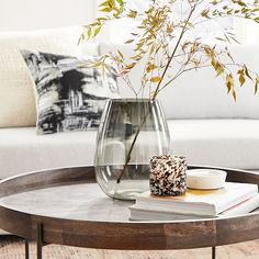 a glass vase filled with flowers sitting on top of a table next to a book