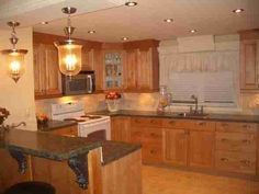 a large kitchen with wooden cabinets and granite counter tops, along with an island in the middle