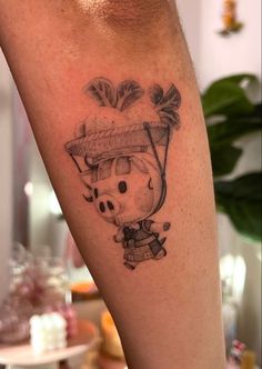 a small pig with a hat on his head is sitting next to a leg tattoo