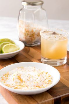 there is a bowl of rice on the table next to a glass and some limes