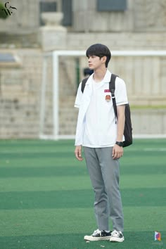 a young man standing on top of a green field