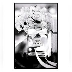 a black and white photo of a chanel bottle with flowers in it