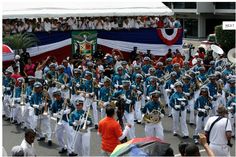 a group of people that are standing in the street with marching instruments and flags behind them