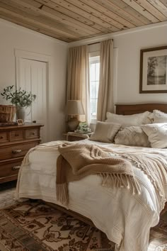 a bedroom with a bed, dresser and window in the corner is furnished with white linens