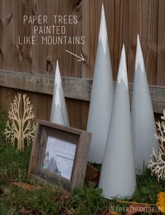 three white cones sitting in the grass next to a wooden frame with an arrow on it