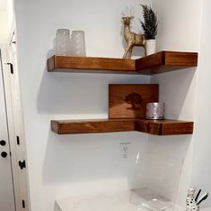 two wooden shelves on the wall above a toilet in a small room with white walls