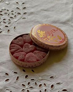 a round tin filled with raspberries sitting on top of a white tablecloth