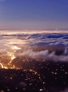 an aerial view of the city lights and clouds