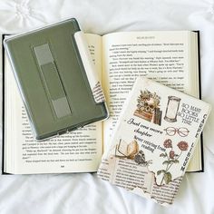 an open book sitting on top of a bed next to a pair of eyeglasses