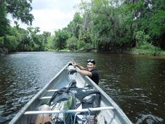 a person in a boat on a river with backpacks and water bottles strapped to the side