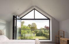 a bedroom with a large window and a bed in front of an open skylight