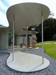 a white building with columns and pillars in the middle of graveled area next to grass