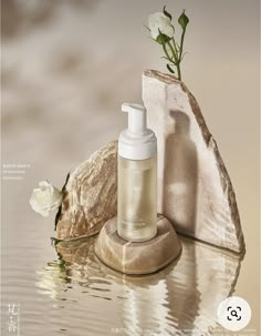 a bottle of lotion sitting on top of a rock next to a body of water