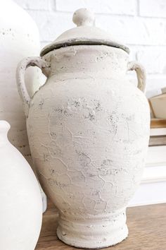 a white vase sitting on top of a wooden table