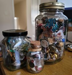 two glass jars filled with different types of buttons