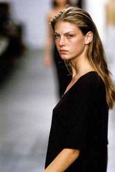 a woman with long hair is walking down the runway wearing a black shirt and jeans