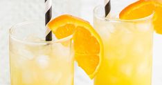 two glasses filled with orange juice and straws