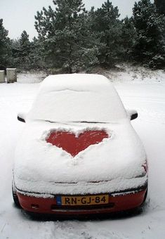 a red car covered in snow with a heart painted on it's front hood