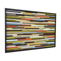 a multicolored wooden wall hanging on the side of a white wall with a black frame