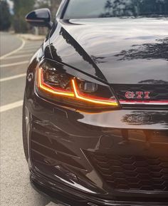 the front end of a black car with its lights on