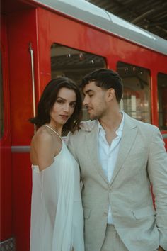 a man and woman standing in front of a red train