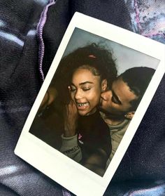 an old photo of a man and woman kissing on top of a purple blanket,