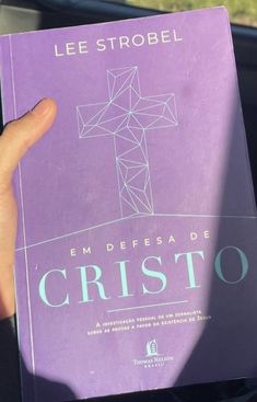 a person holding up a purple book with a cross on it's front cover