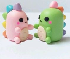 two small toys are sitting next to each other on a white surface with blurry background