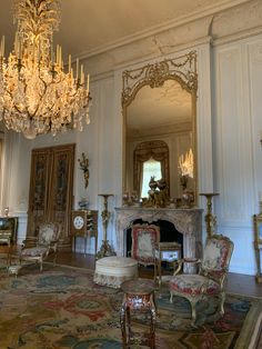 an ornate living room with chandelier, chairs and fireplace in the middle of it