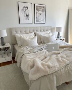 a laptop computer sitting on top of a bed covered in white comforter and pillows