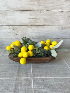 a wooden bowl filled with lemons on top of a table