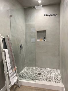 a walk in shower sitting inside of a bathroom next to a white towel on a rack