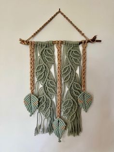 a wall hanging made out of macrame and rope with leaves attached to it