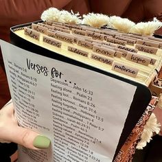 a person holding up a large book with writing on it's pages, in front of a brown couch