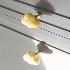 two yellow knobs on the side of a white cabinet with light coming through them