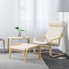 a white chair and ottoman in a living room with a lamp on the side table