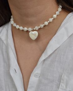 Pretty choker necklace handcrafted with real mother of pearl beads and an adorable heart pendant. Includes a 3" extender chain. MATERIALS. Mother of pearl (4mm and 8mm round beads, 20mm heart) 14k gold filled hardware Lobster clasp with 3" extender chain Model wearing 14" What is mother of pearl? Technically termed "nacre", it is the iridescent inner lining of certain mollusk shells. It is also the material that pearls are composed of.  PLEASE NOTE. Natural materials like freshwater pearls and g Pretty Choker Necklace, Soft Girl Aesthetic, Y2k Coquette, Pearl Heart, Pendant Choker, Soft Girl, Pearl Beads, Round Beads, Heart Pendant