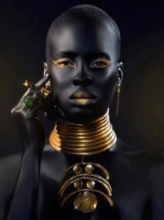 an african woman with gold jewelry on her neck and hands in front of her face