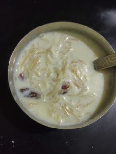 a bowl filled with noodles and sauce on top of a black table next to a spoon