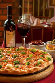 a pizza sitting on top of a table next to a bottle of wine and bowls of food