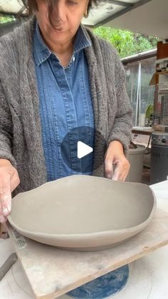 a woman is making a bowl out of clay