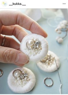 a person holding some kind of white brooch with pearls on it's back