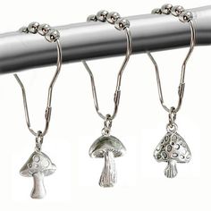 three silver colored earrings hanging from a metal bar with balls on it and mushrooms attached to them