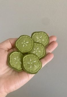 four green buttons in the palm of someone's hand, with dragonflies on them