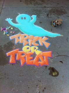 there is a chalk drawing on the ground that says trick or treat with a ghost and sprinkles